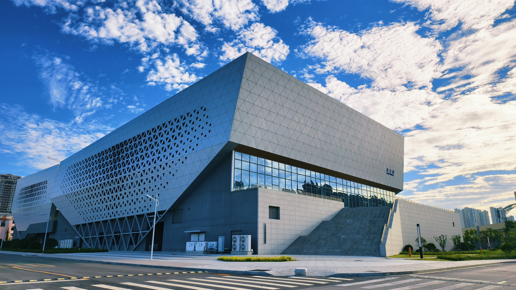 体育馆实景，蓝天白云下轮廓鲜明的现代建筑