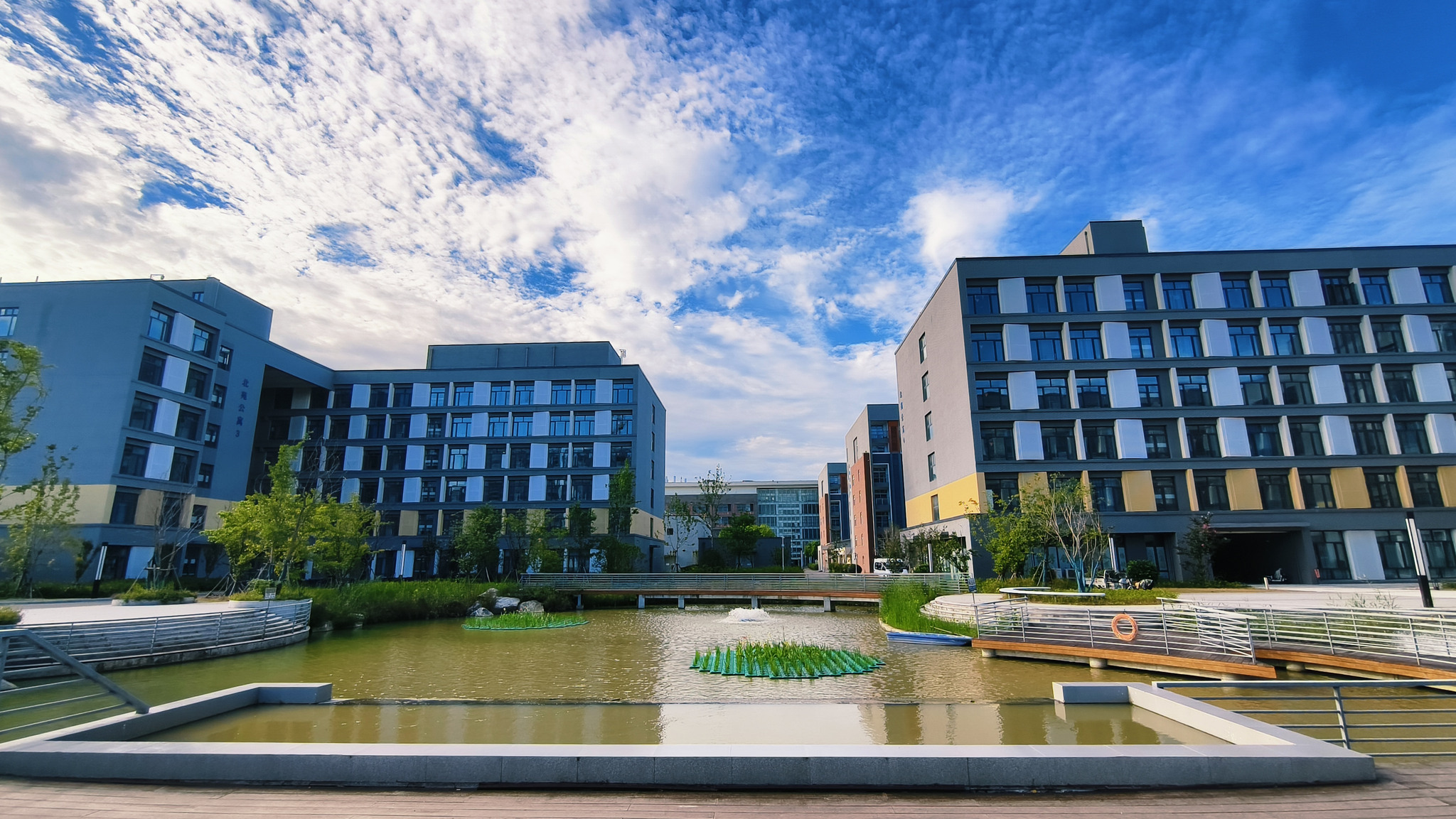 北苑宿舍楼群实景，建筑与水景在蓝天下相映